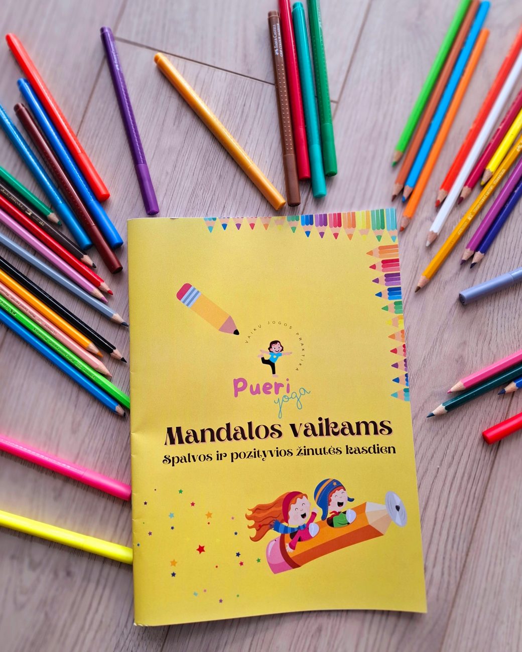 Mandalų spalvinimo knygelės „Mandalos vaikams" viršelis su spalvotais pieštukais