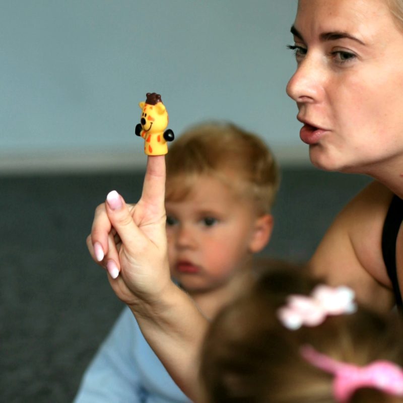 Mokytoja su pirštine lėle veda žaidimą mažiems vaikams