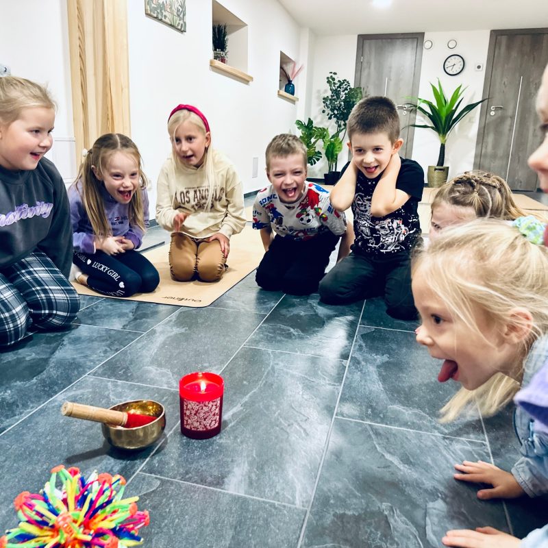 Vaikai sėdi ratu aplink dainuojantį dubenį ir žvakę